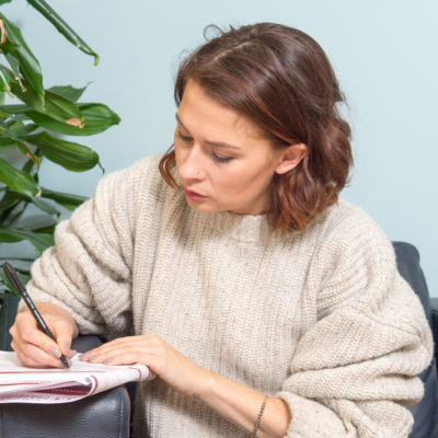 Woman in jumper filling out the complaint form on the sofa